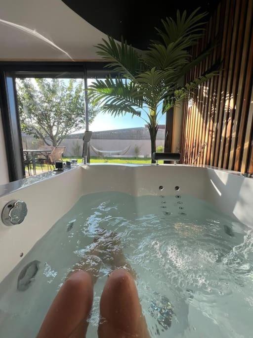 une personne dans une baignoire avec ses pieds dans l'établissement ESCAPE ZEN Oasis tropicale & Spa privatif, à Loon-Plage