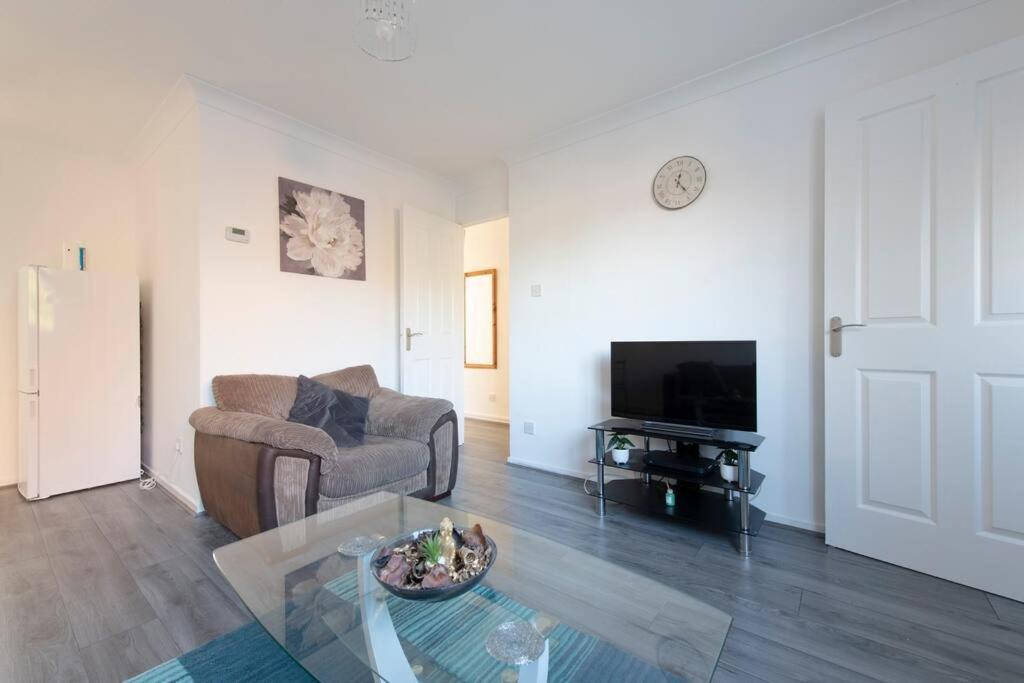 uma sala de estar com um sofá e uma televisão em Lovely 1 bedroom maisonette close to Airport, Town and Train Station em Luton