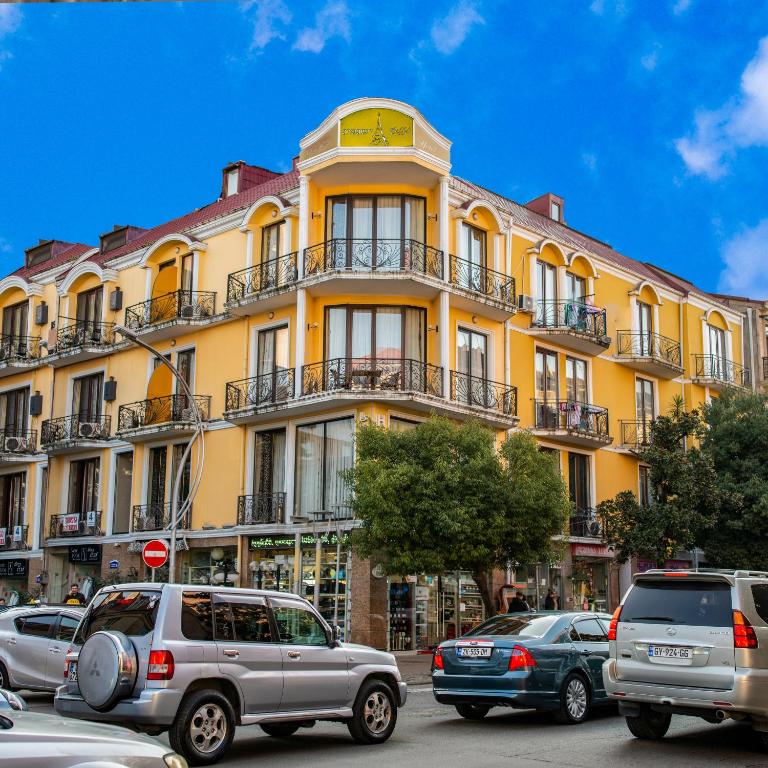 a yellow building with cars parked in front of it at Eiffel Hotel in Batumi