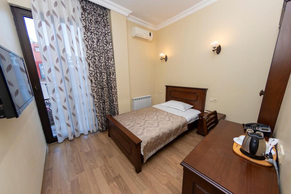 a bedroom with a bed and a table and a window at Eiffel Hotel in Batumi