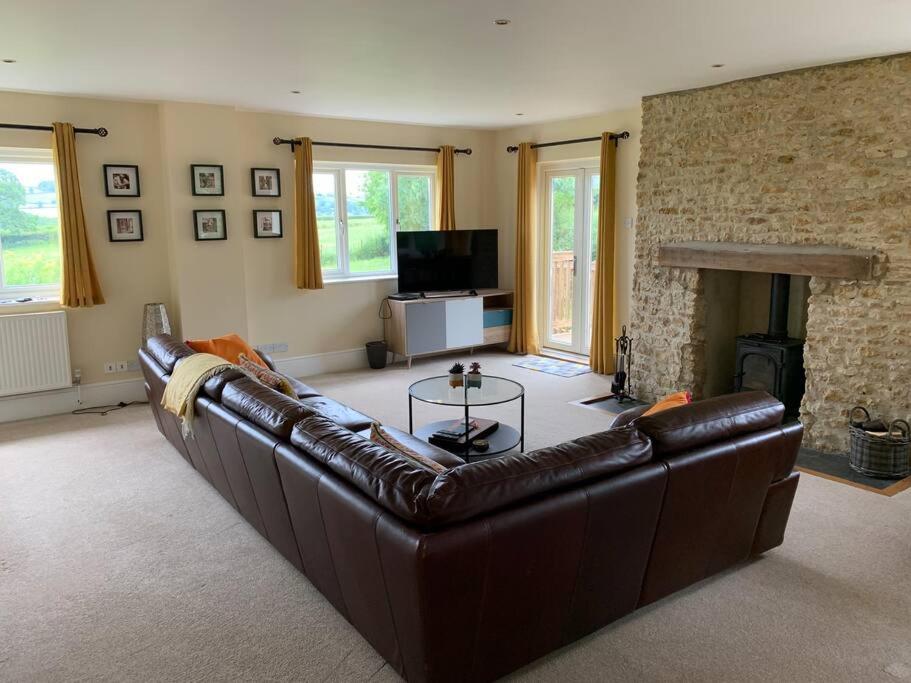 a living room with a leather couch and a fireplace at Cosy Cottage in the heart of Black Down Hills in Yarcombe