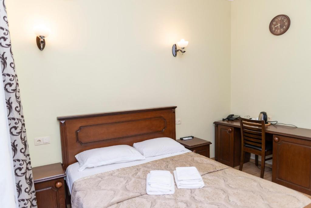 a bedroom with a bed with two white towels on it at Eiffel Hotel in Batumi
