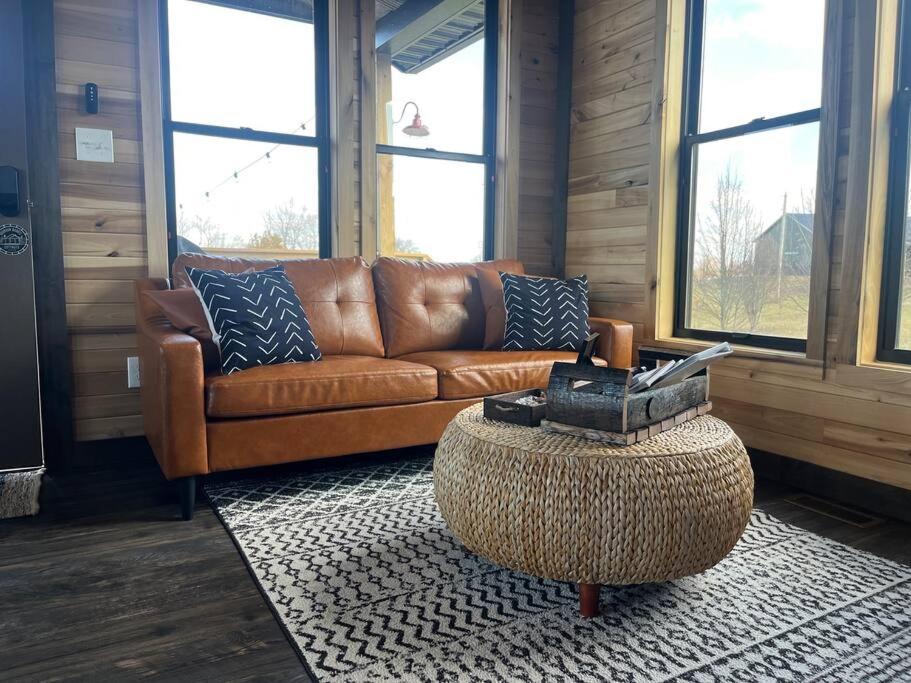 uma sala de estar com um sofá de couro castanho e uma mesa em Bourbon Barrel Cottages #2 of 5 on Kentucky trail em Lawrenceburg