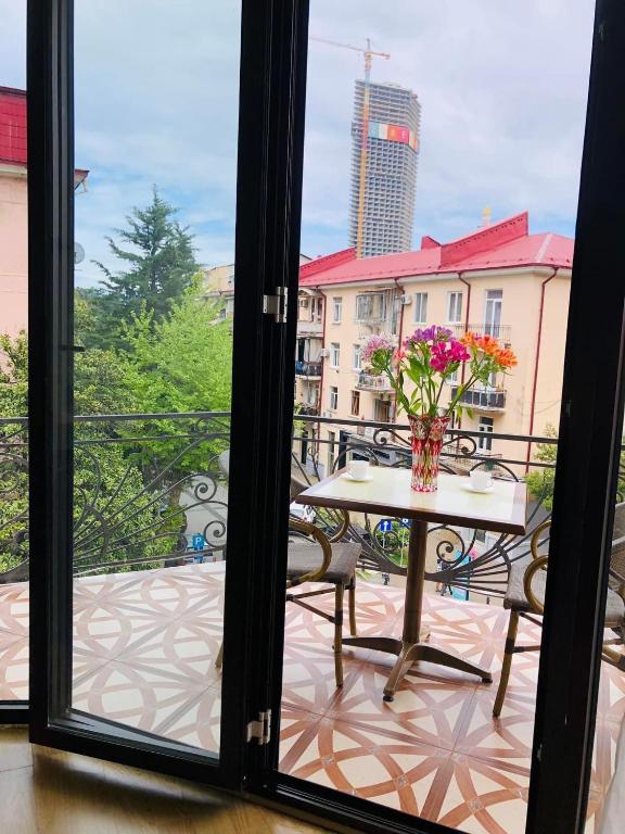 a table with a vase of flowers on a balcony at Eiffel Hotel in Batumi