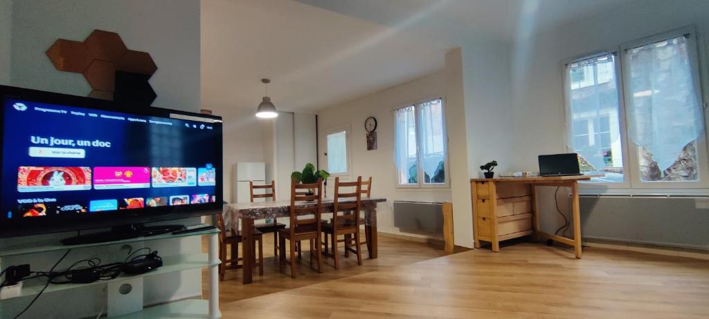 a living room with a large television and a dining room table at Tranquil House 10min from Disneyland Paris in Bussy-Saint-Georges