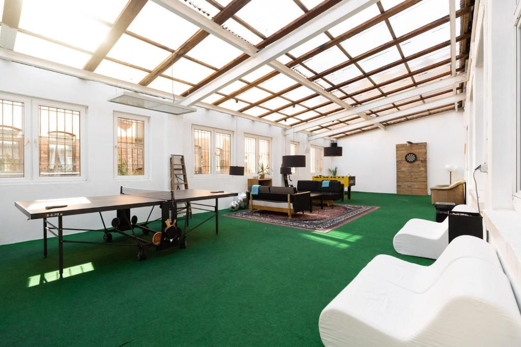 a large room with green carpet and a table and chairs at 230 m2 Loft mit eigenem Wintergarten mit Tischtennis & Dart, kostenloser Parkplatz in Erfurt