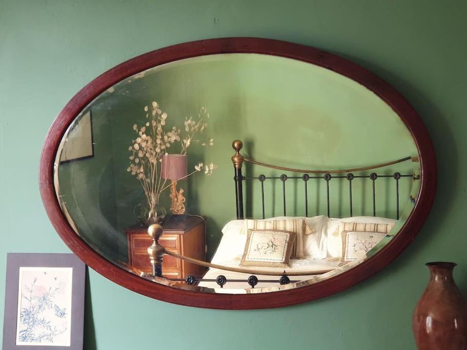 een spiegel aan de muur met een bed met kussens bij The Writer's House in Canterbury