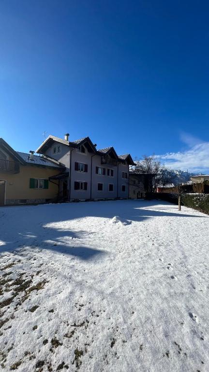 a snow covered parking lot in front of a house at Al BELVEDER in Levico Terme