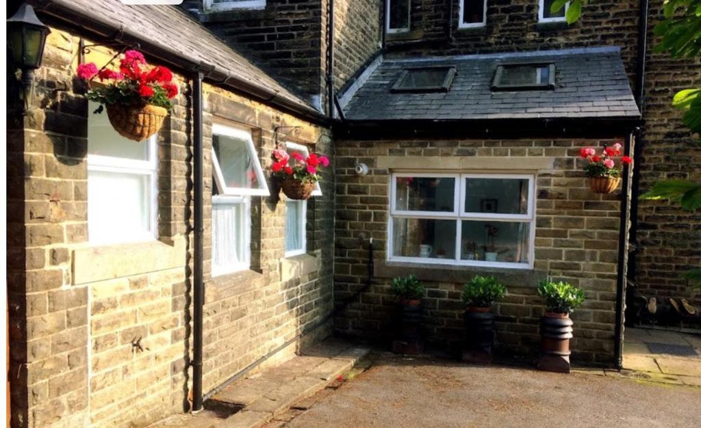 a brick house with two windows and two potted plants at Private annex to Victorian villa, with kitchen and Free parking in Todmorden