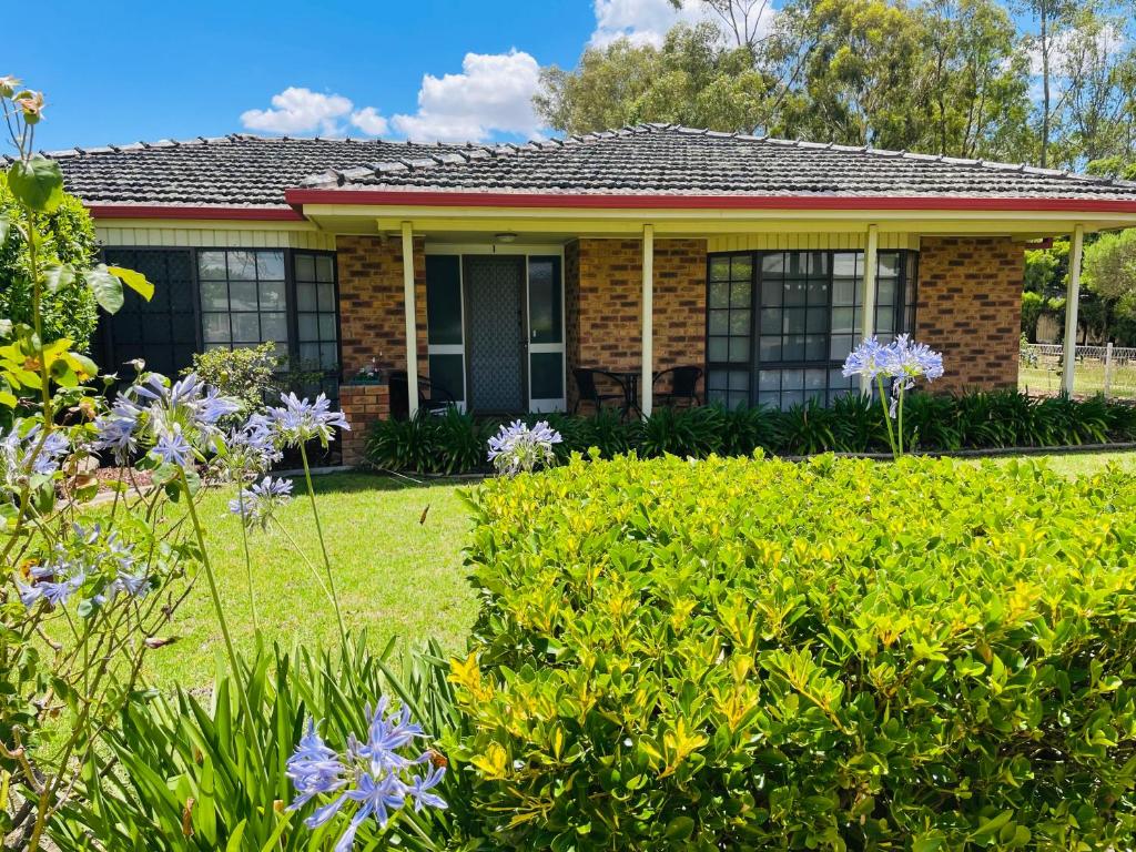 ein Haus mit einem Hof mit lila Blumen in der Unterkunft Peaceful 2 Bedroom Home in Wagga Wagga