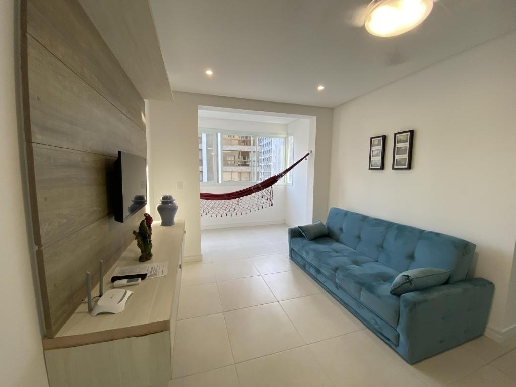 sala de estar con sofá azul y TV en Apartamento em Torres-906 - Uma quadra do mar, en Torres