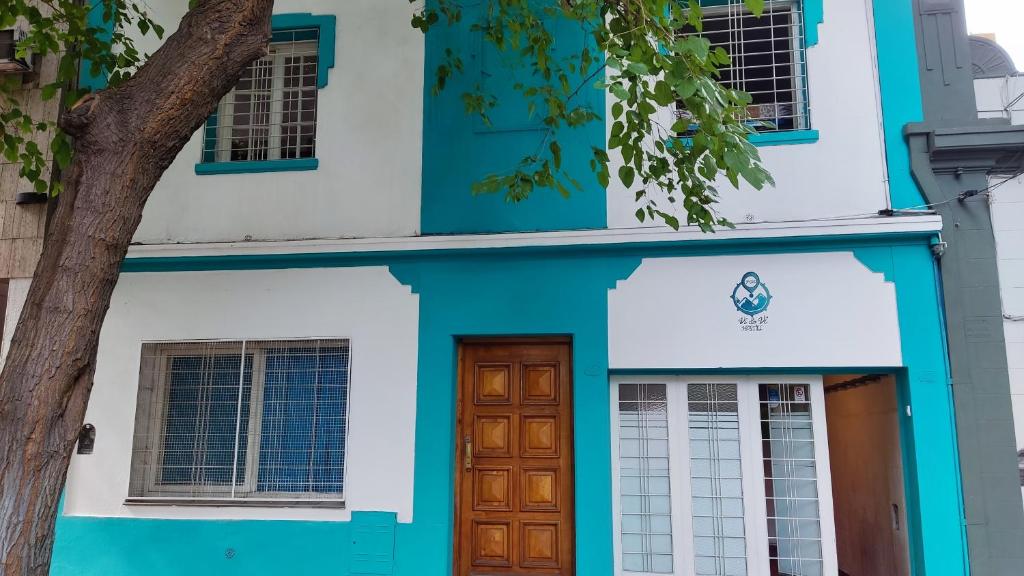 una casa blu e bianca con una porta in legno di VI&VI HOSTEL MENDOZA a Mendoza