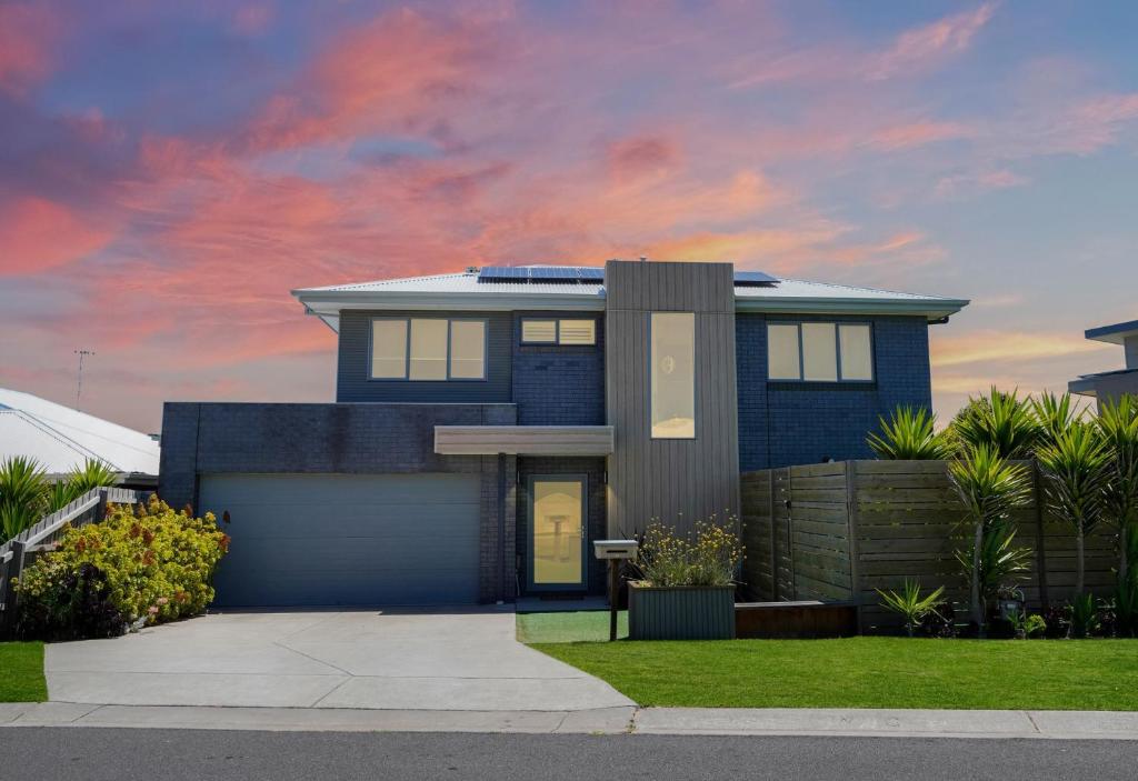 ein blaues Haus mit Sonnenuntergang im Hintergrund in der Unterkunft Tara Cuan in Port Fairy