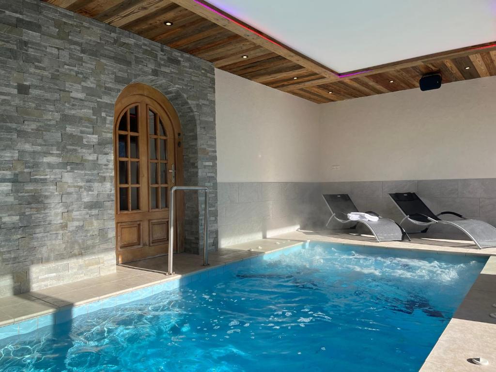 a large swimming pool with blue water in a room at GITE BALNEO LES AMARYLLIS in Taninges