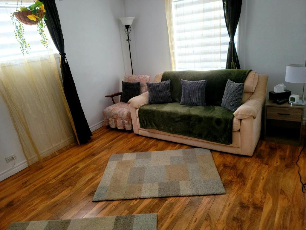 sala de estar con sofá verde y suelo de madera en Downtown apartment next to highway netflix+wifi en Edmundston