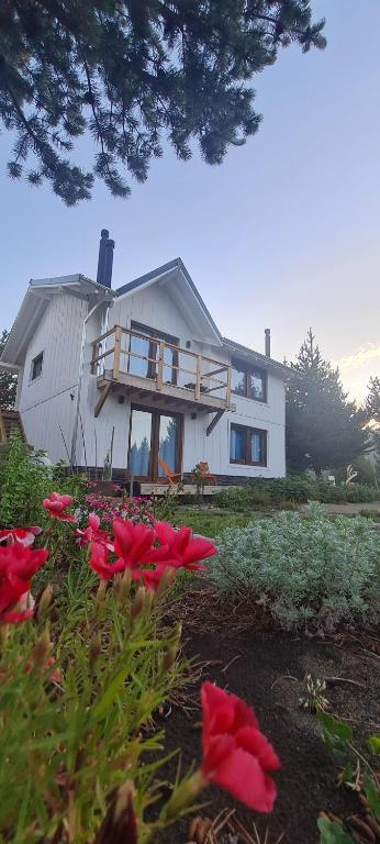 a house with red flowers in front of it at Mountain House departamentos de montaña in Villa Meliquina