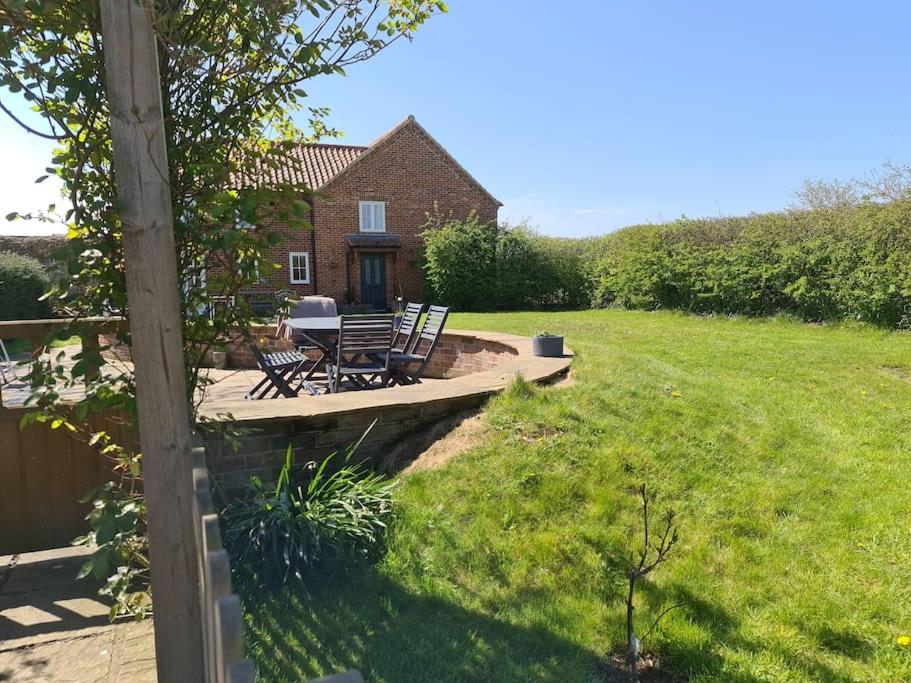 a patio with two chairs and a table in a yard at Brisley North Norfolk cosy cottage garden pub and walks in Beetley