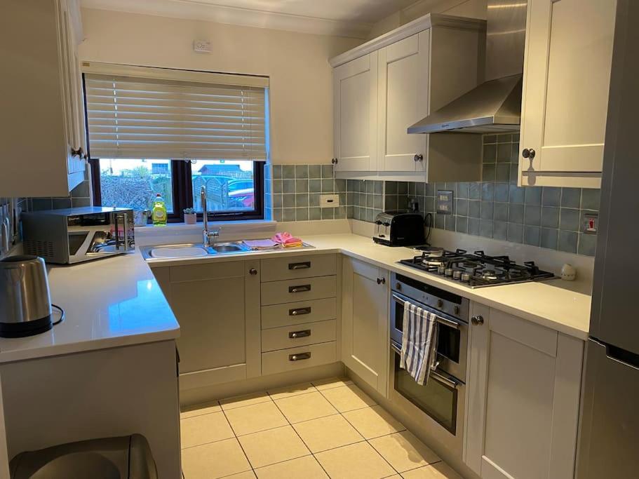 a kitchen with white cabinets and a stove top oven at Braunton Breaks - Ambrose Cottage in Braunton