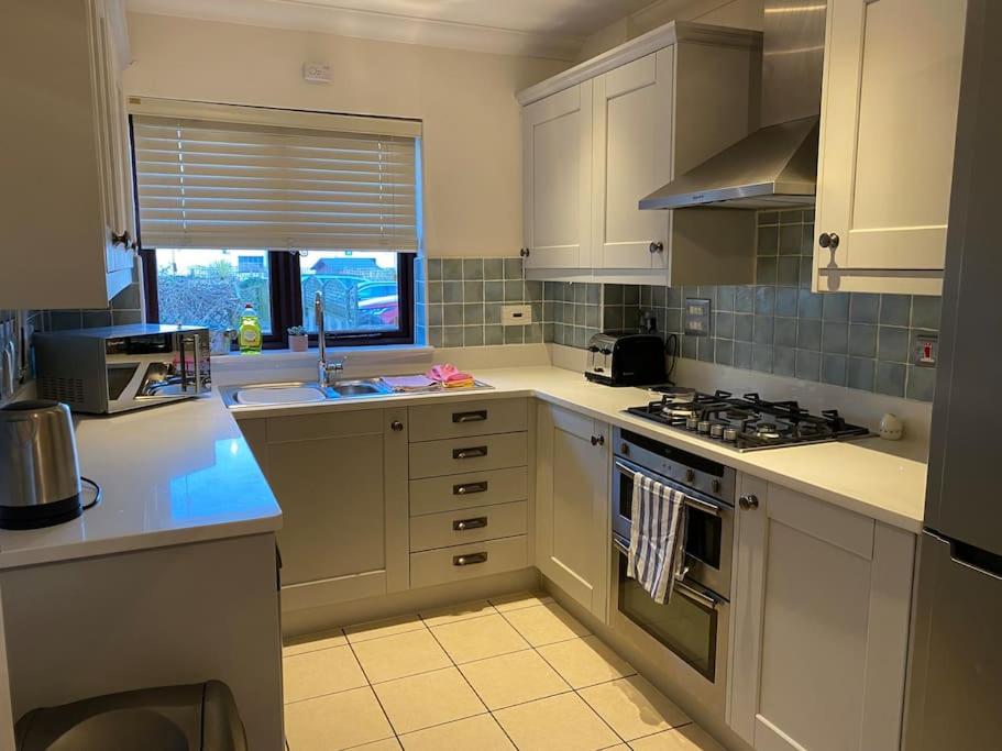 eine Küche mit weißen Schränken und einem Herd mit Backofen in der Unterkunft Braunton Breaks - Ambrose Cottage in Braunton