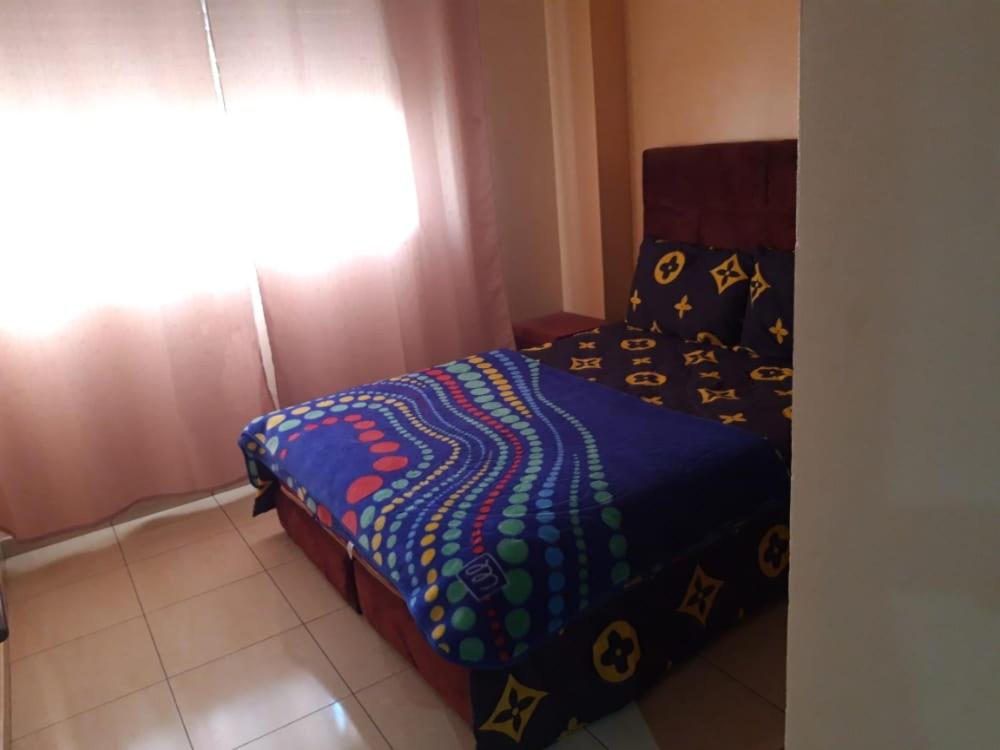 a bedroom with a bed with a blue comforter and a window at Islane in Agadir