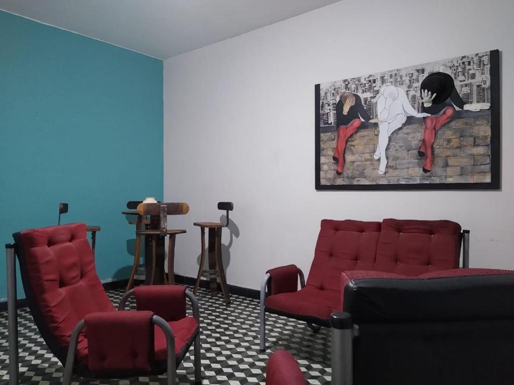 una sala de espera con sillas rojas y una pintura en la pared en Casa céntrica El Rosal (cabaña) en San Rafael