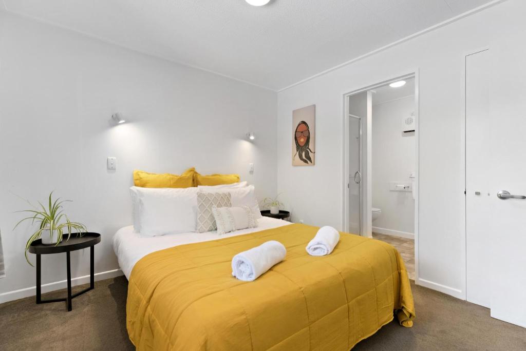 a bedroom with a large yellow bed with towels on it at Central town apartment in Queenstown