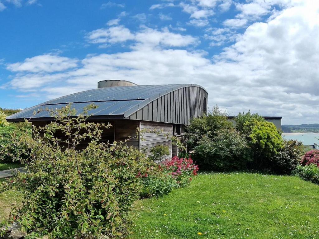 une maison avec un toit métallique sur un champ d'herbe dans l'établissement Villa in Locquirec with Stunning Sea Views, à Locquirec