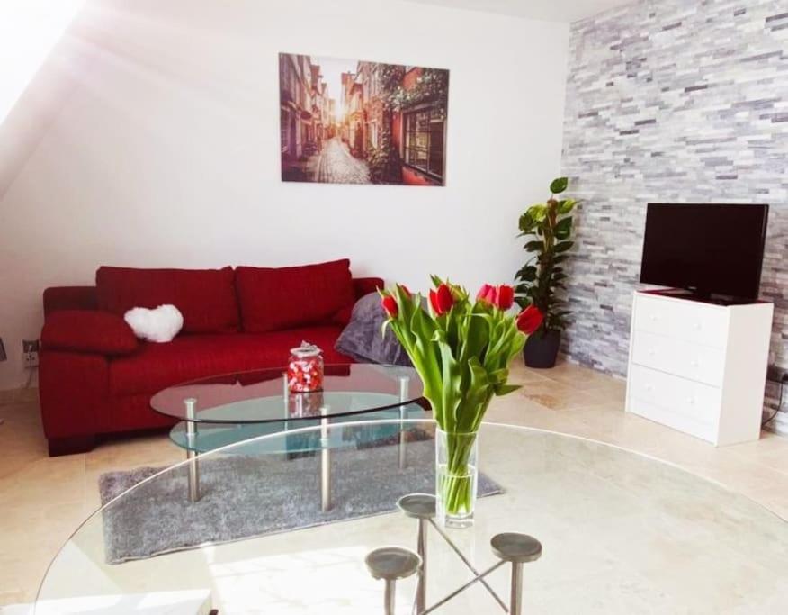 - un salon avec un canapé rouge et une table en verre dans l'établissement UNMITTELBAR am ULMER MÜNSTER - Cozy Apartment, à Ulm