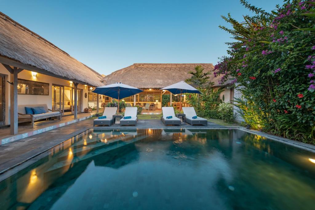 a swimming pool with two chairs and umbrellas at Villa Damai Manis in Seminyak