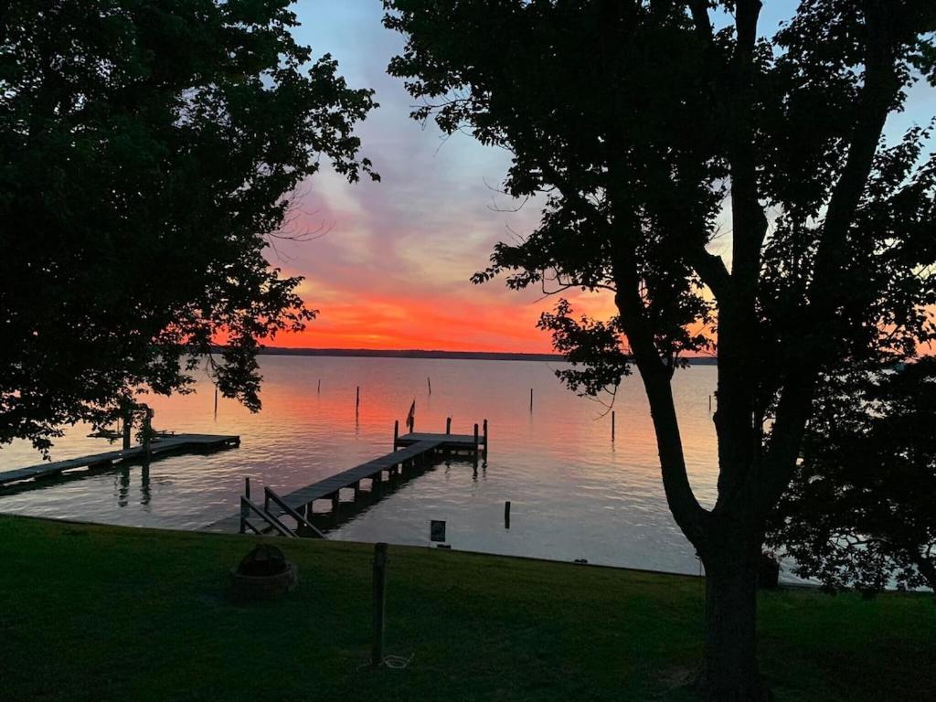 un muelle en un lago con una puesta de sol en el fondo en Lands End Lodge River House, en Tappahannock