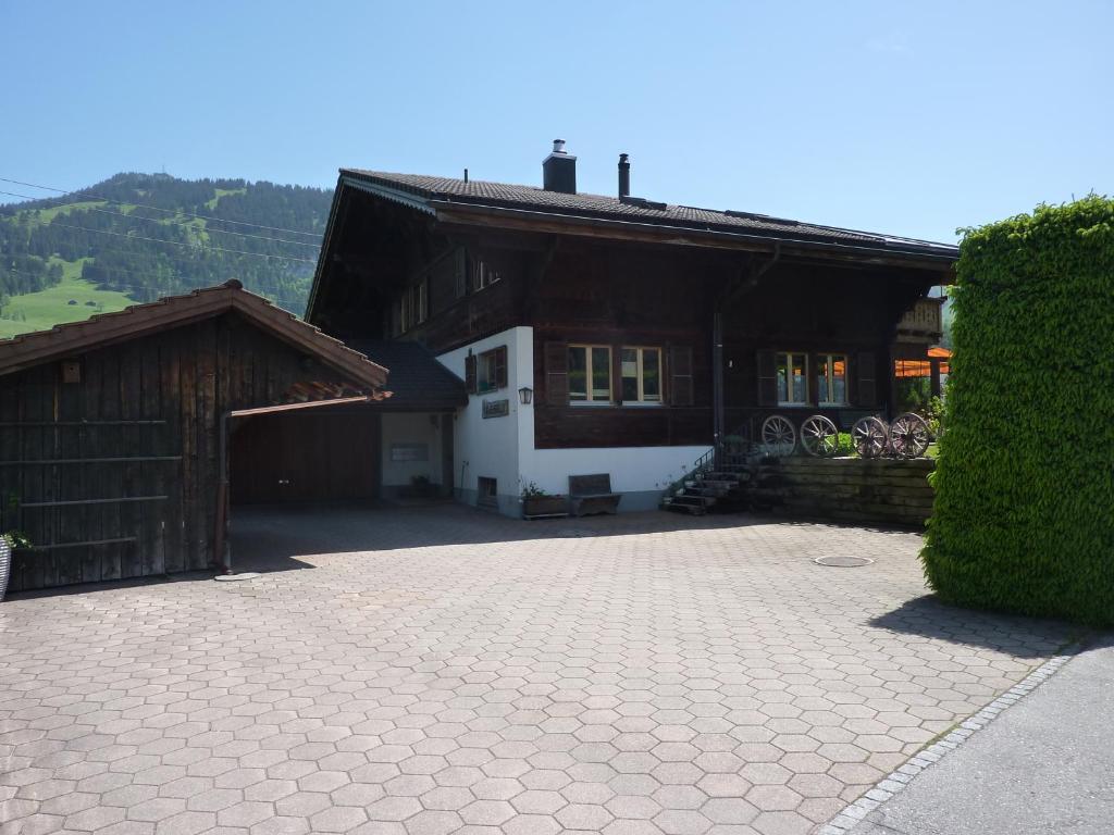 a house with a brick driveway next to a building at Chalet Aebnetbode in Gstaad