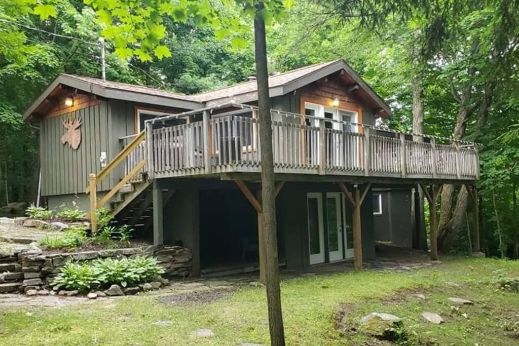 a cabin in the woods with a large deck at Muskoka Ski Chalet in Huntsville