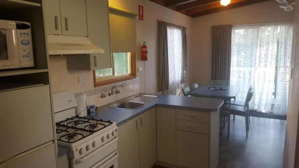 a kitchen with a stove and a sink and a counter at Alexandra Parklife Deluxe Studio 2 in Alexandra