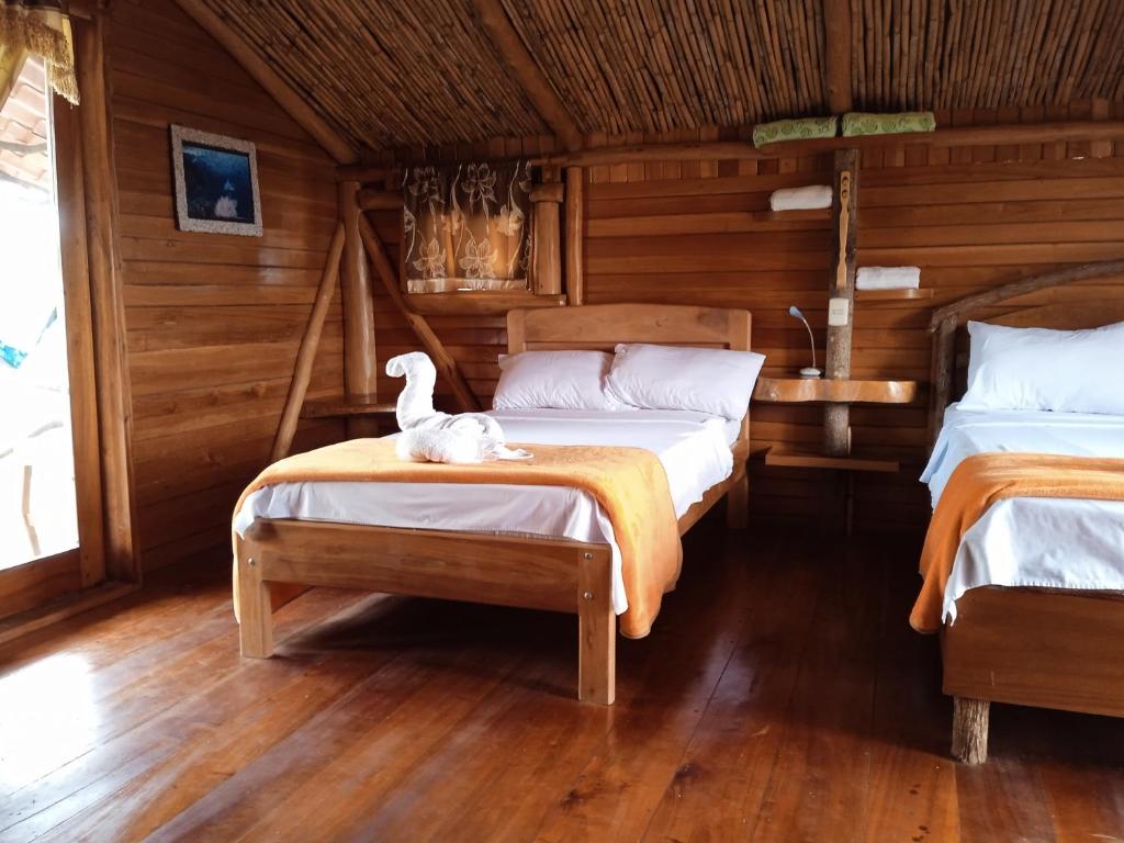 a room with two beds and a white cat sitting on a bed at El Pajas in Puerto Velasco Ibarra