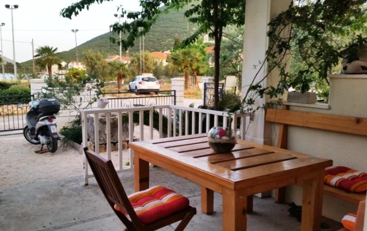 a wooden table and chairs on a balcony with a motorcycle at Villa Mali Ston (3588) in Mali Ston