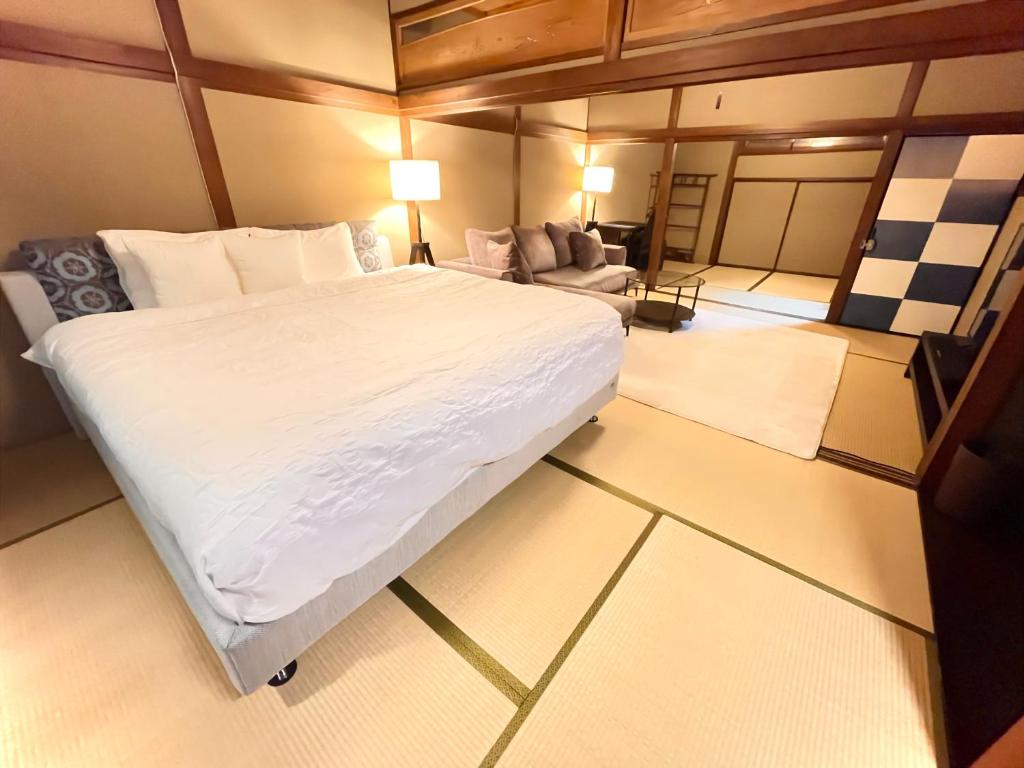 1 dormitorio con 1 cama blanca grande y 1 sofá en Machiya no Yado Gu en Nara