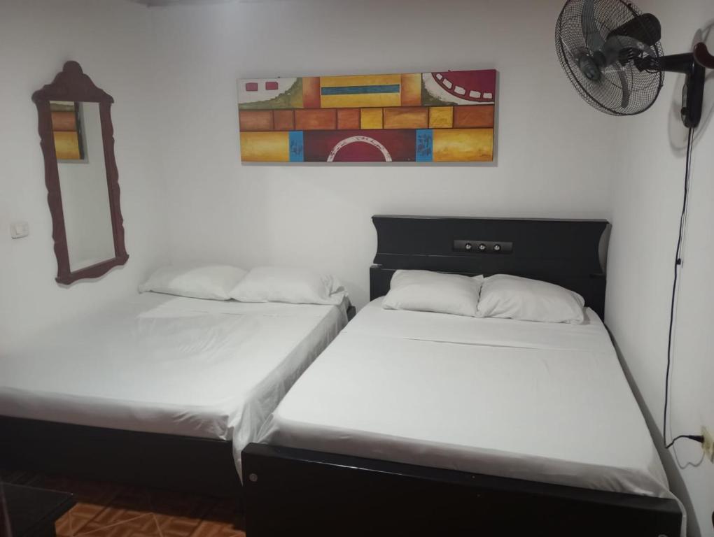 two beds in a room with a painting on the wall at Hotel Bethesda in Aguachica