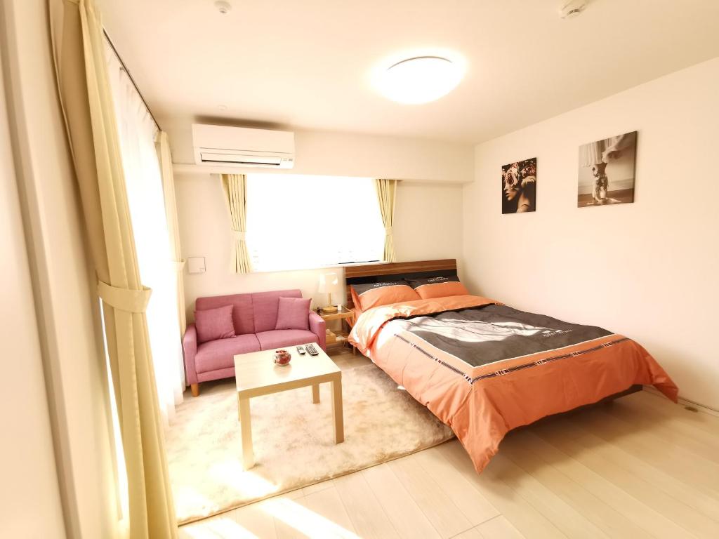 sypialnia z łóżkiem i różowym krzesłem w obiekcie KIKI HOUSE 新小岩 w Tokio