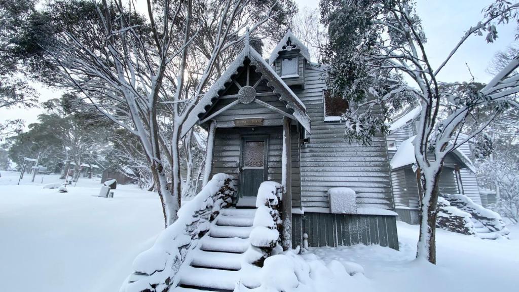 una pequeña casa de madera con nieve en las escaleras en Alpine Retreat en Dinner Plain