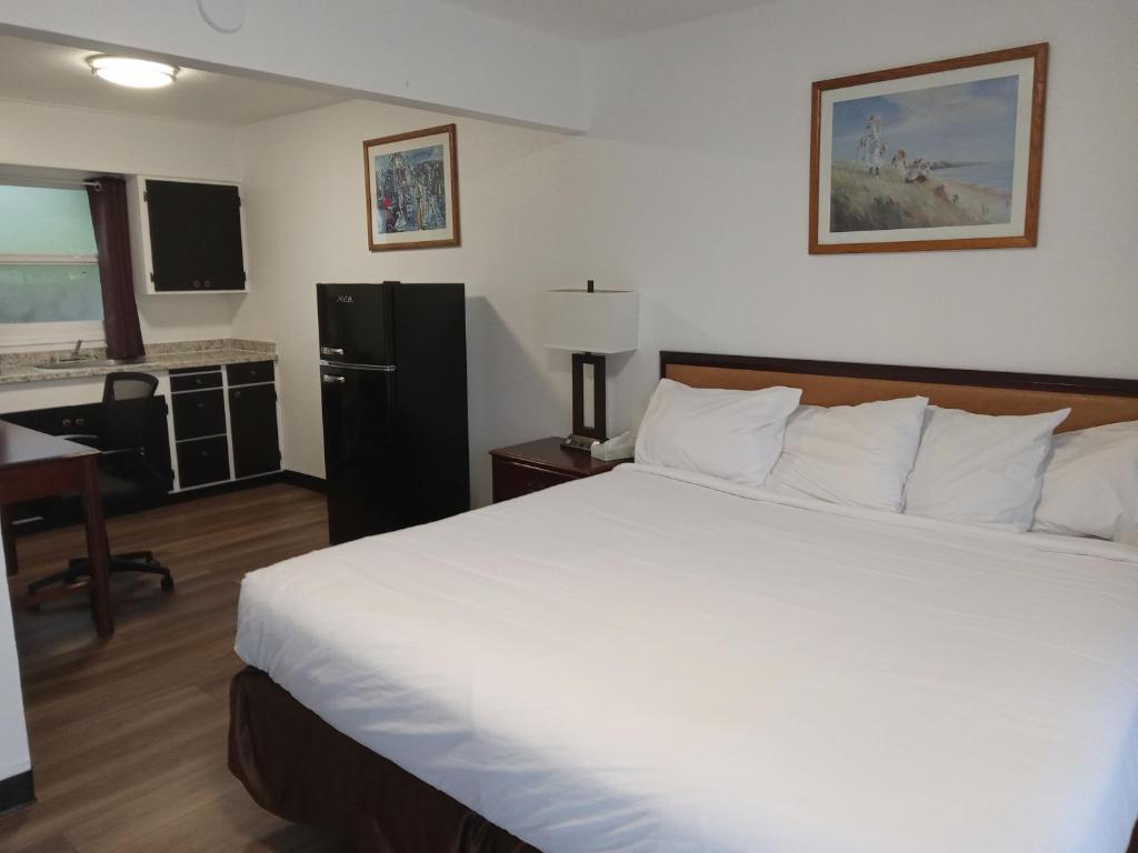 1 dormitorio con 1 cama blanca grande y cocina en Blue Coast Inn & Suites, en Brookings