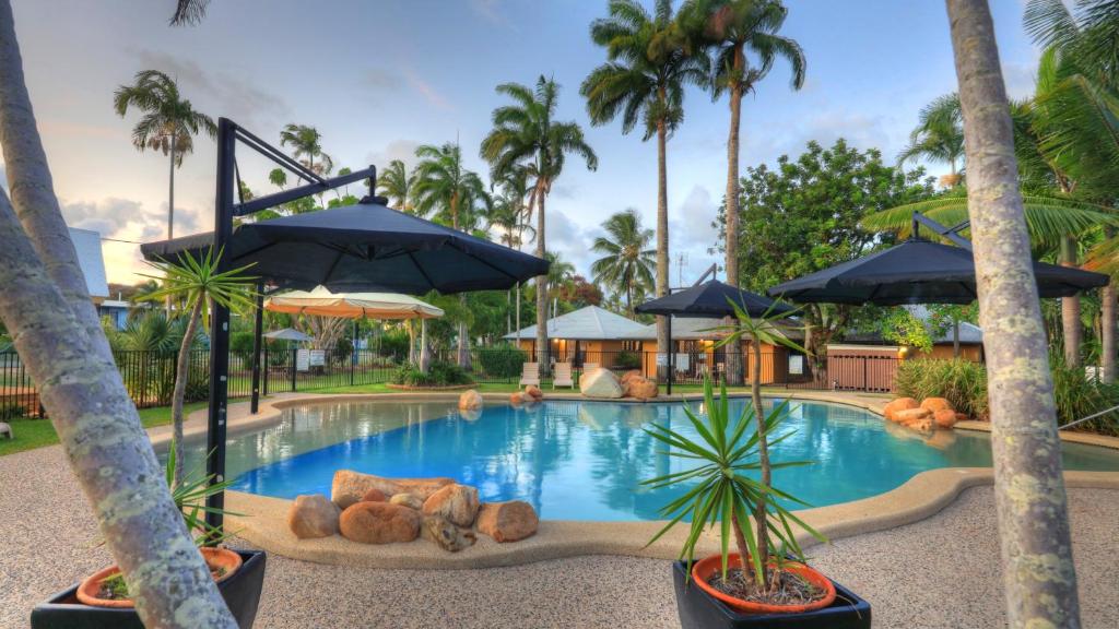 uma piscina num resort com palmeiras e guarda-sóis em BIG4 Lucinda Wanderers Holiday Park em Lucinda