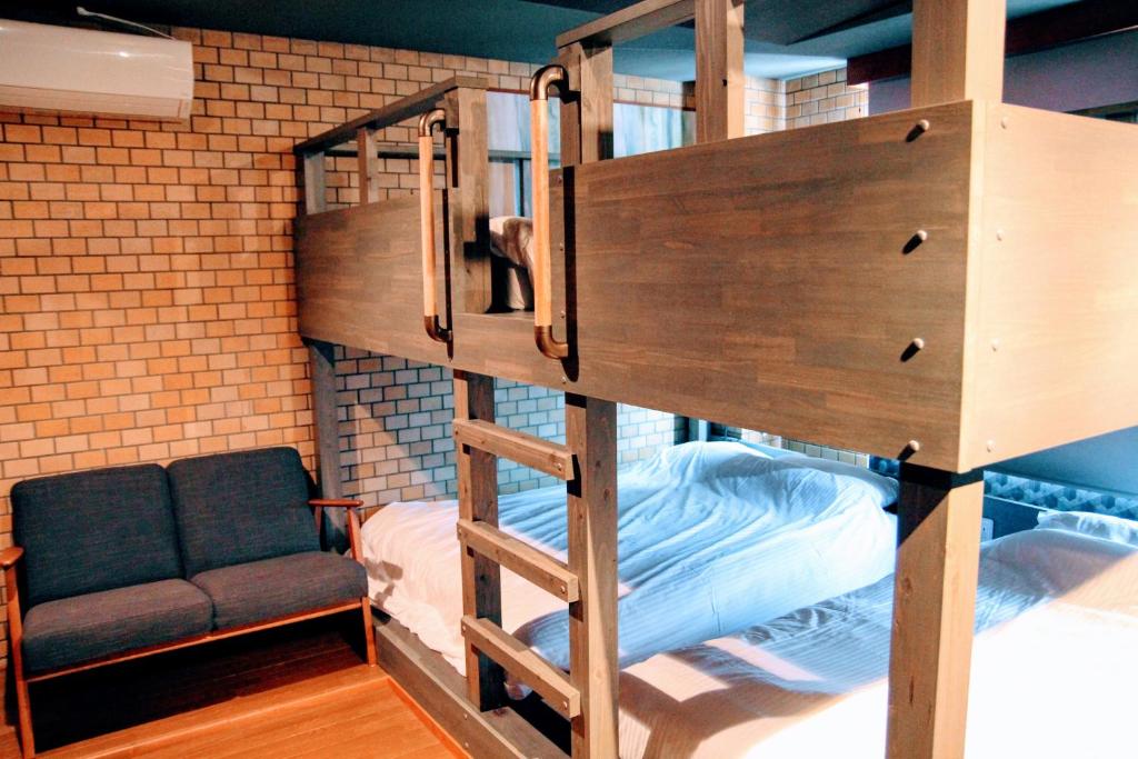 Cette chambre comprend un lit superposé avec une échelle et un canapé. dans l'établissement Share Hotel 198 Beppu, à Beppu