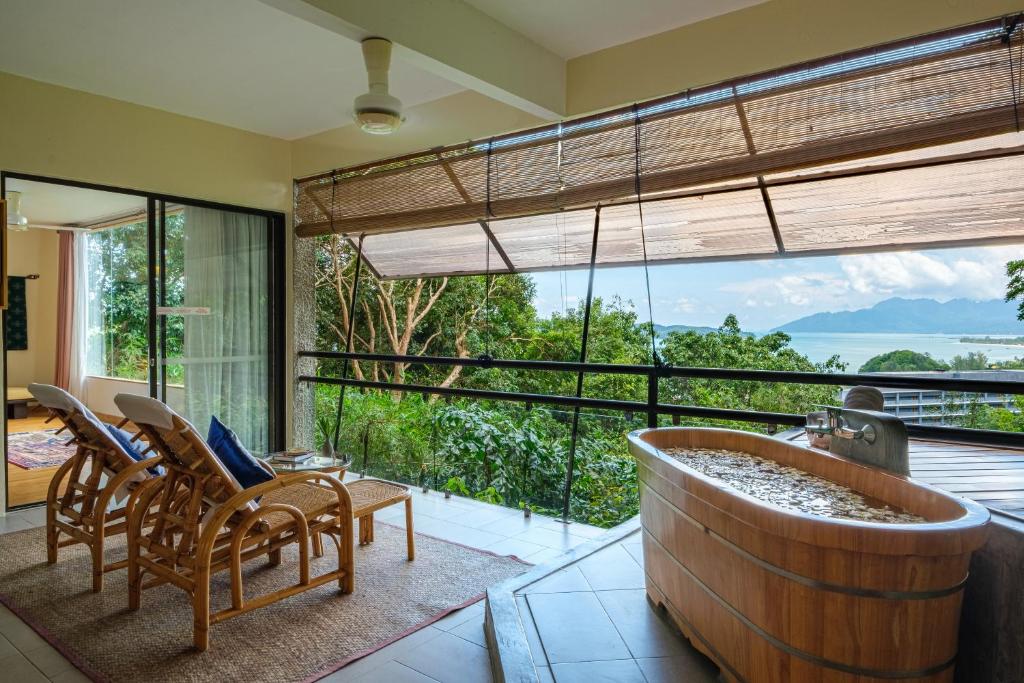 una grande vasca al centro di una stanza con sedie di Ambong Rainforest Retreat a Pantai Cenang