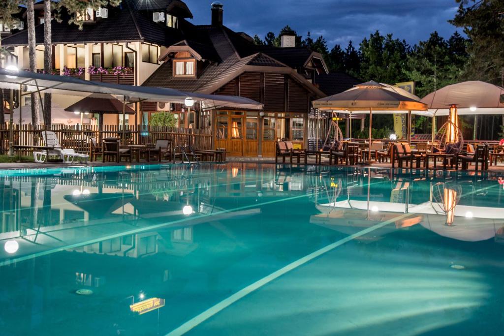 a pool with tables and chairs in front of a house at Hotel Zlatiborska Noc in Užice