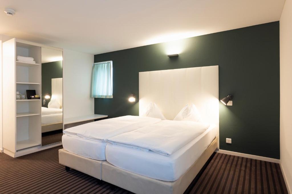 a bedroom with a large white bed and a mirror at Self Check-In Hotel David 22 in St. Gallen