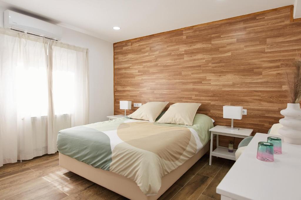 una camera da letto con un letto e una parete con accenti in legno di El Hortal i lloo a El Cuervo