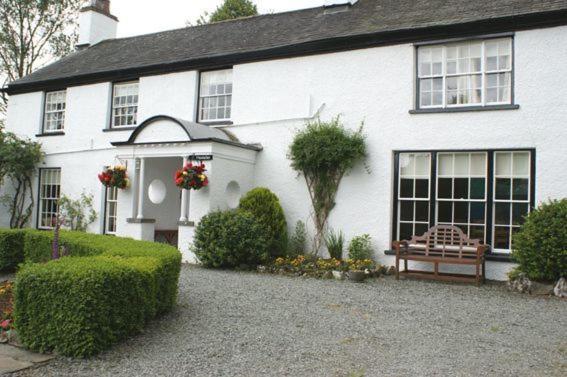 Uma casa branca com um banco à frente. em Old School House em Hawkshead