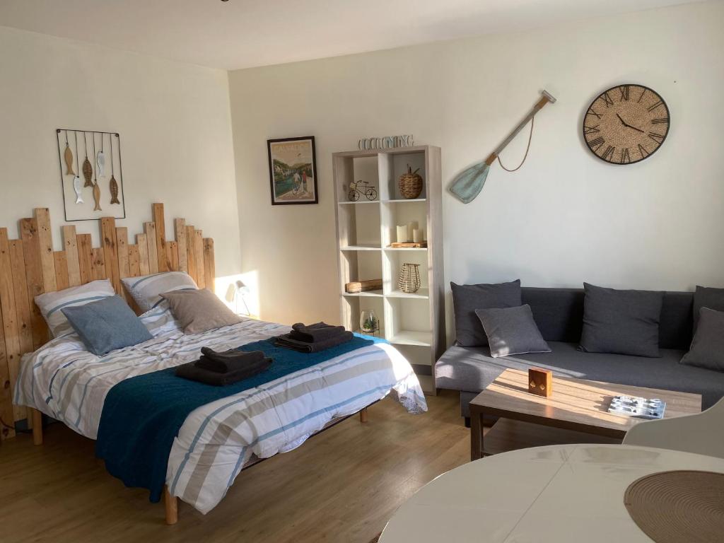 een slaapkamer met een bed, een bank en een klok bij Le cocon sainte Catherine in Honfleur