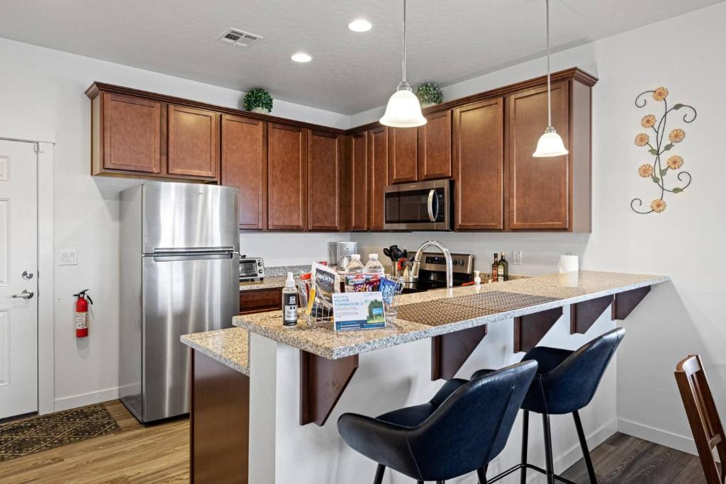 une cuisine avec des placards en bois et un grand îlot avec des tabourets de bar dans l'établissement Village Townhouse 2, à Boise