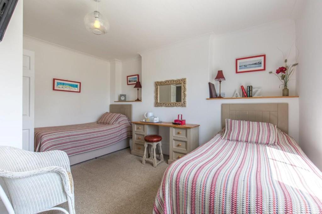 a bedroom with two beds and a desk with a mirror at The Globe Inn in Wells next the Sea